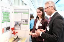 Dr. Hartmut Klusik, Vorstandsmitglied der Bayer AG, lässt sich von Anna Behrmann ihr Projekt erklären